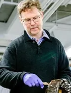Image of Prof Paul A Meehan in purple gloves holding tools